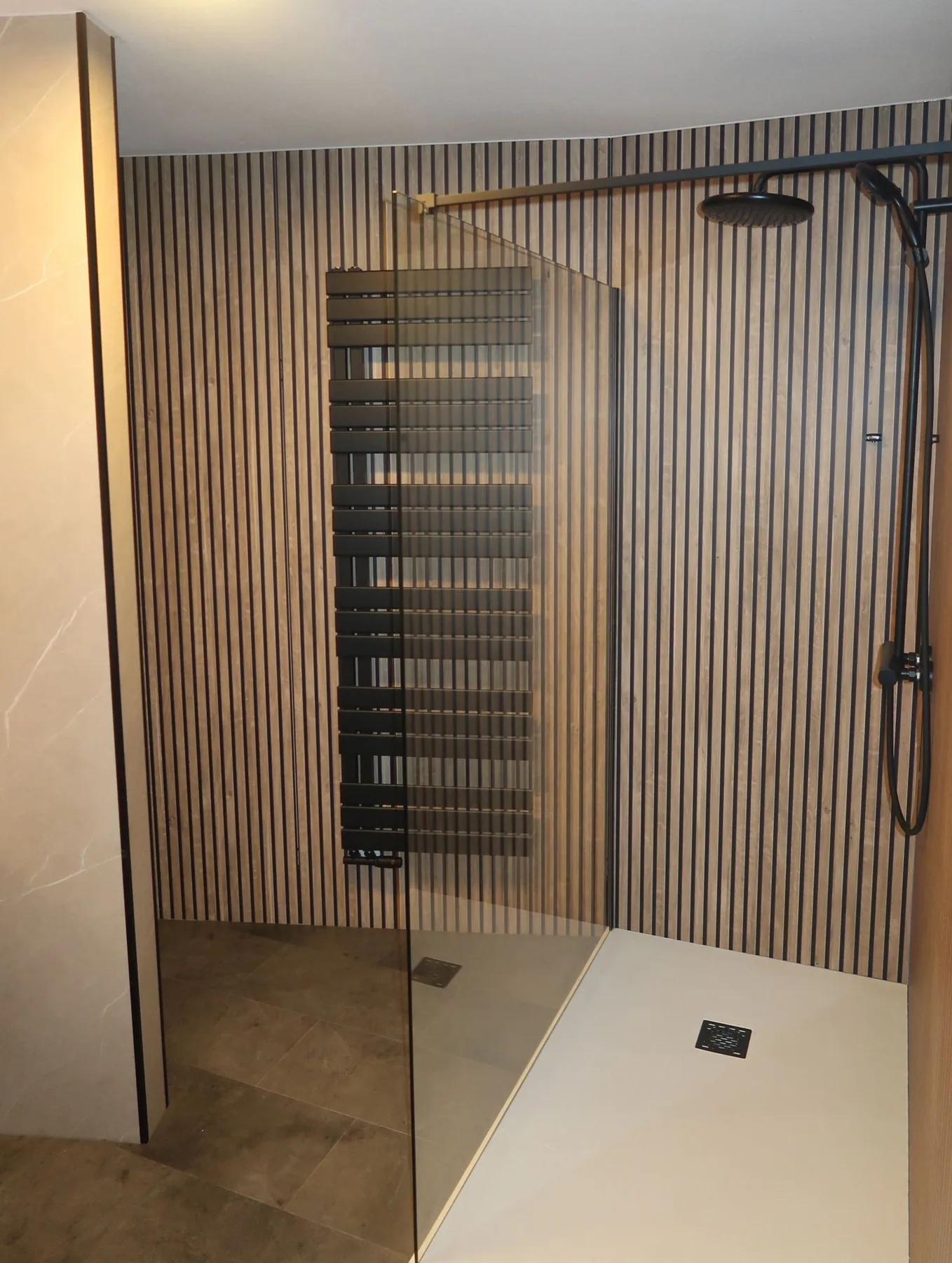 Inloopdouche met houtlook lamellenwand, zwarte handdoekradiator en zwarte regendouche