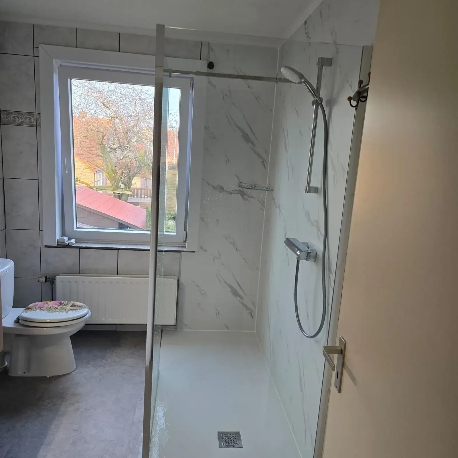 Inloopdouche met glazen wand en witte marmerlook wandpanelen