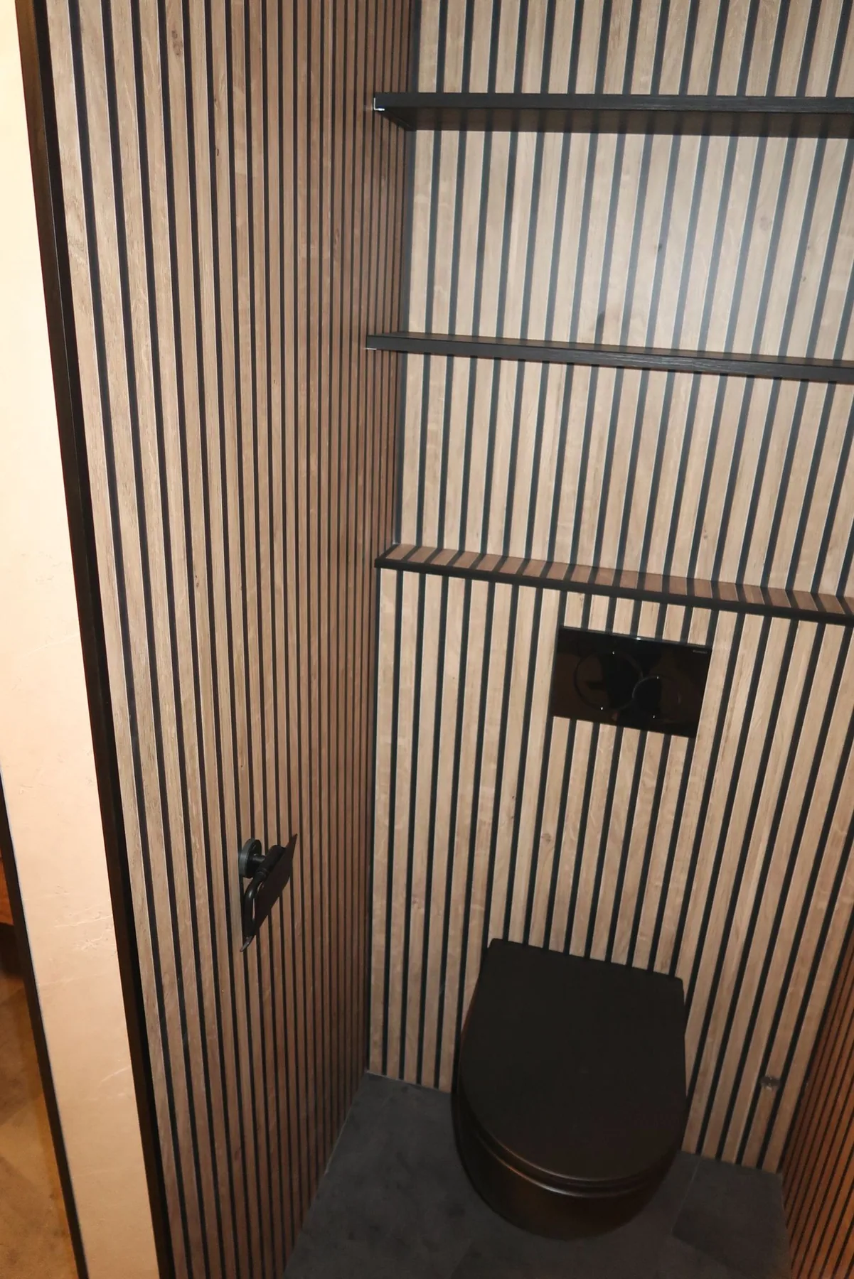 Toilet met houtlook lamellenwand, zwart hangtoilet en drie zwarte wandplanken