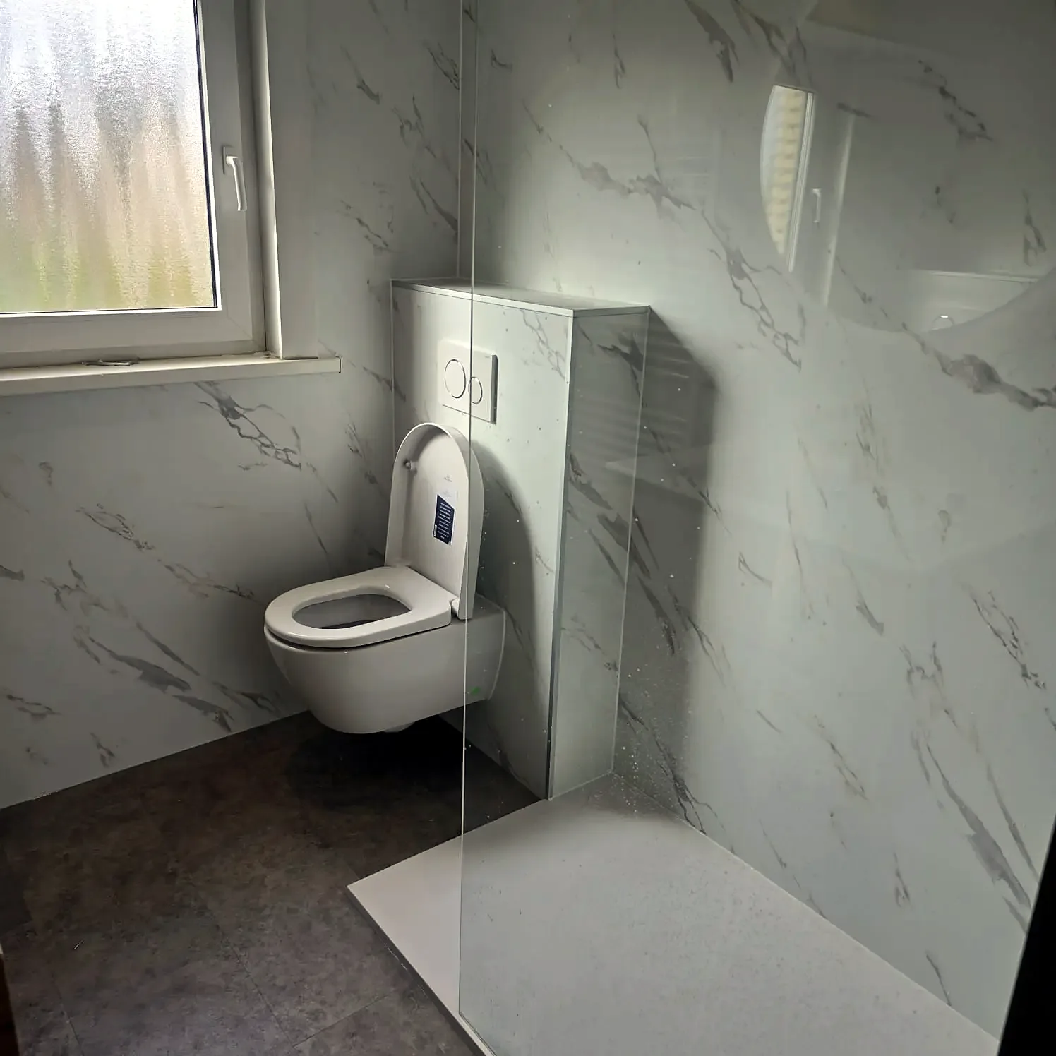 Toiletruimte met witte marmerlook wandpanelen en hangtoilet