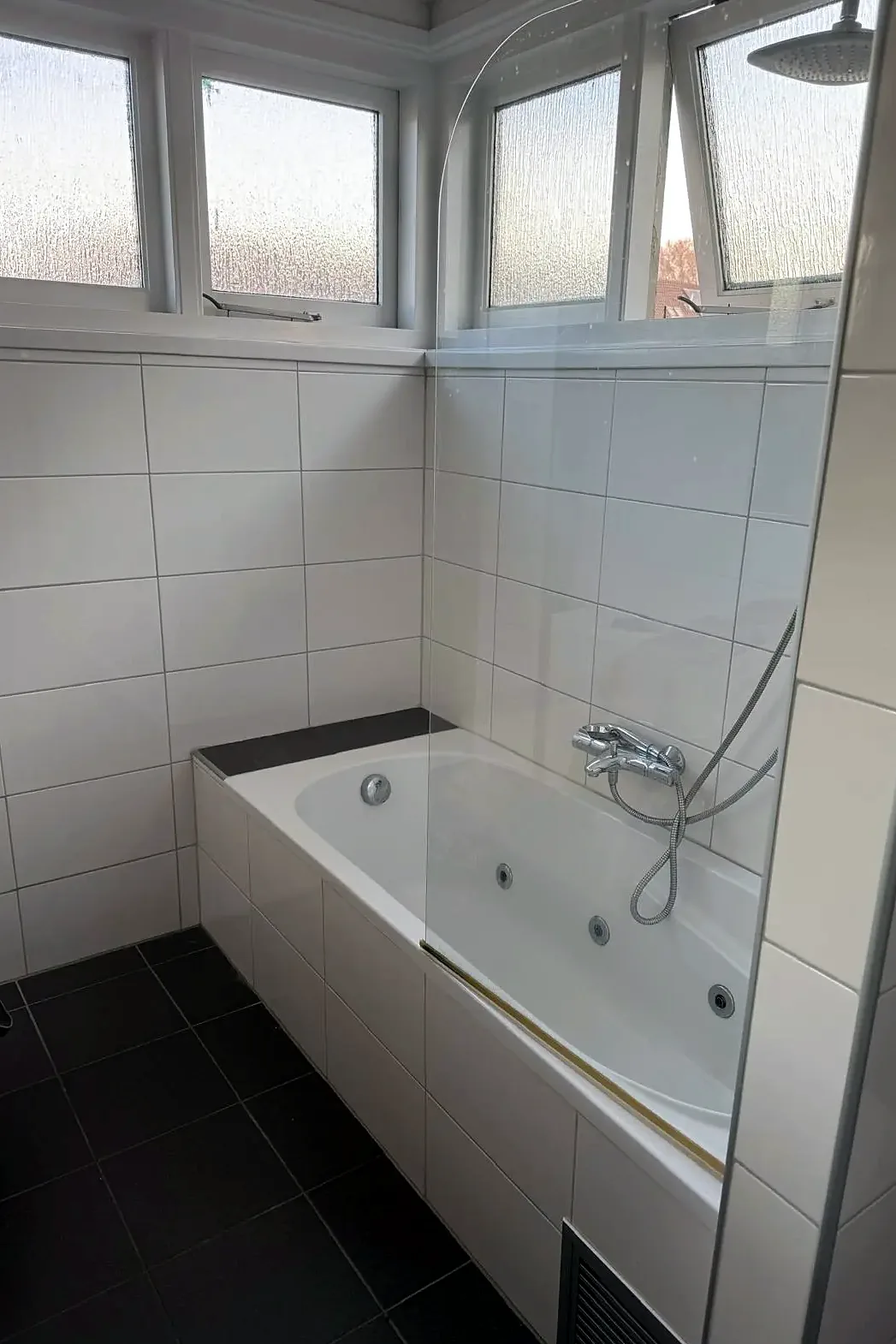 Badkamer met ligbad en witte wandtegels