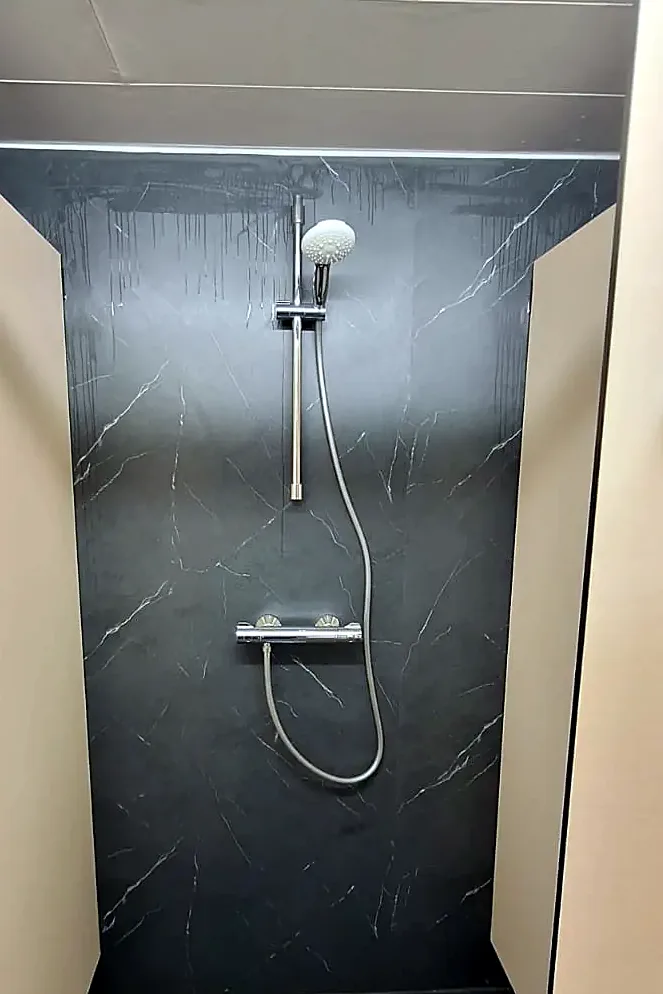 Dezelfde douche met zwarte marmerlook wandpanelen en een nieuwe douchekraan