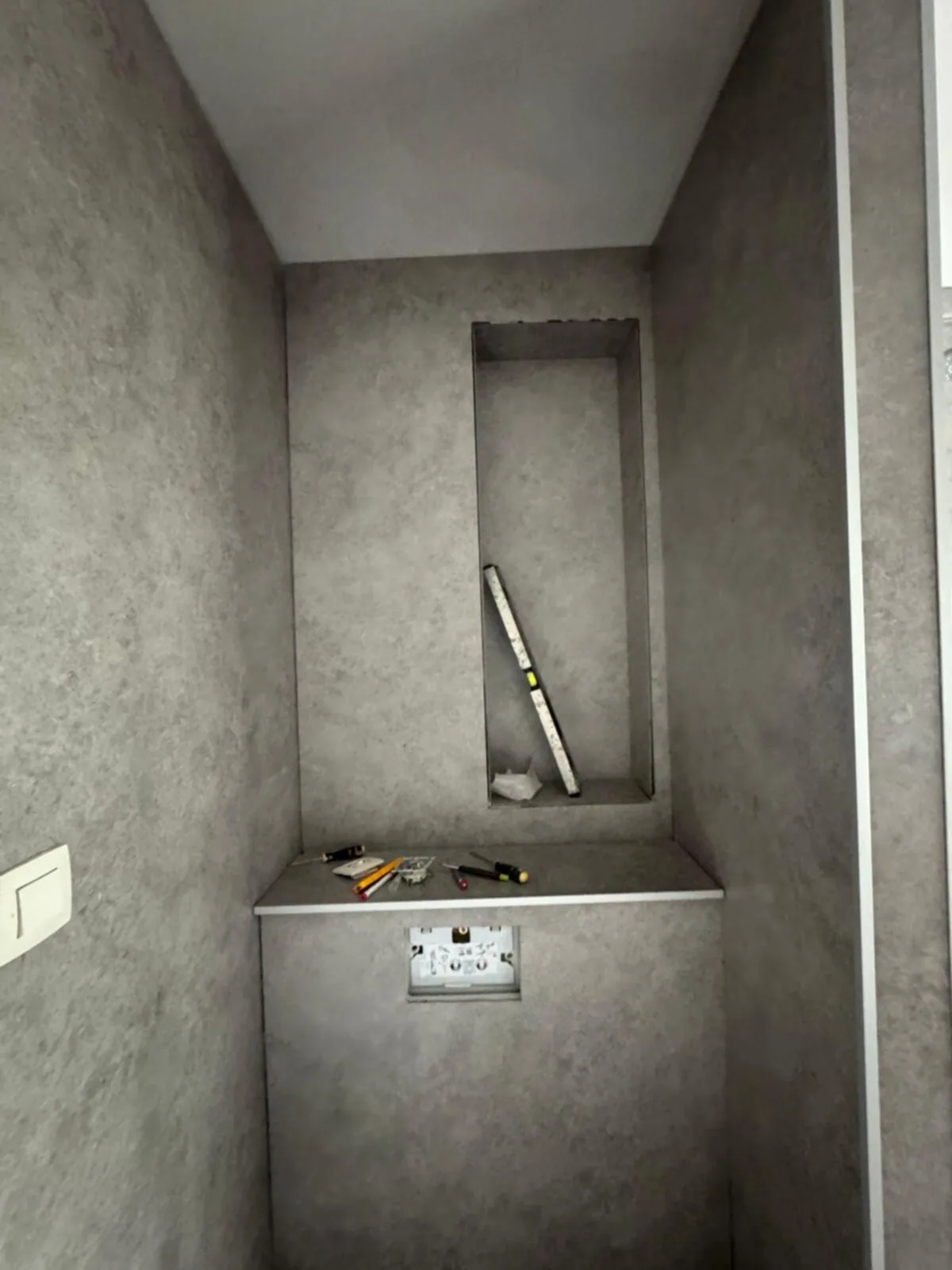 Voorzetwand voor een hangtoilet met nis, bekleed met grijze steenlook wandpanelen
